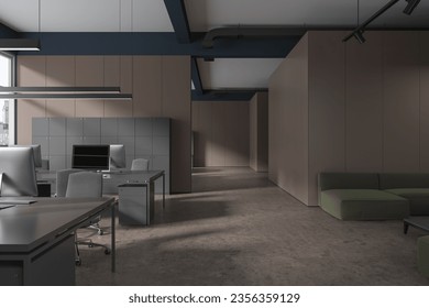 Dark office interior with shared table and pc monitors in row, lounge zone with sofa on grey concrete floor. Coworking and chill space in corporate loft. 3D rendering