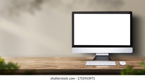desktop computer on wood table backgorund with sunlight window create leaf shadow on wall with blur indoor green plant foreground.panoramic banner mockup for display of product.3d rendering