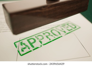 A detailed close-up showcases an 'APPROVED' stamp on a document, symbolizing formal acceptance in business or legal settings, emphasizing authority and decision-making. - Powered by Shutterstock