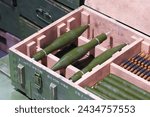 Detailed view of organized military ammunition, including green artillery shells and bullets, securely stored in sturdy wooden crates, prepared for transport.