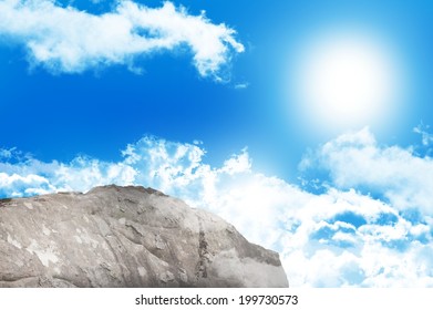 Digitally generated large rock overlooking blue sky