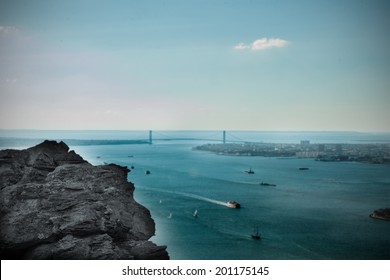 Digitally generated large rock overlooking harbour with bridge