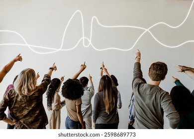 A diverse group of people pointing at a wall with light trails. Mixed genders and ethnicities. Collaborative and interactive scene with a focus on light trails. Diverse people pointing upwards.