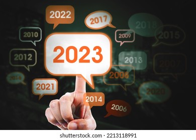 Double Exposure Of Hands Pressing 2023 Numbers On Virtual Screen To Beginning Year With Past Years Background In Night City