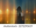 A double exposure of a mysterious hooded figure. silhouetted against the sky. With blurred abstract glowing lights. With an atmospheric, moody edit.