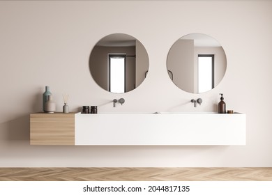 Double vanity with paired materials, two on trend round mirrors and taps on the beige wall of a shower room with parquet style flooring. A concept of modern bathroom interior design. 3d rendering