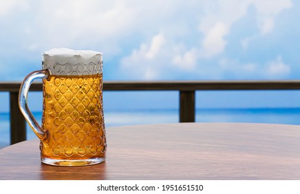 Draft or craft beer in a tall clear glass With beer foam on top And there are bubbles in the glass. Cold beer in a glass, placed on a wooden table on the beach, the sea during the day. 3D Rendering - Powered by Shutterstock