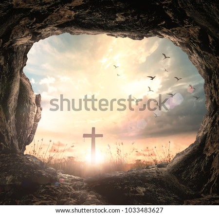 Easter Religious concept: Empty tomb stone with cross on meadow sunrise background