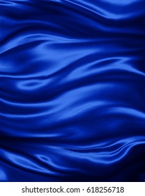 elegant luxury sapphire blue background with wavy draped folds of cloth, smooth silk texture with wrinkles and creases in flowing fabric