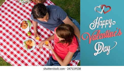 Elevated view of two friends lying on a blanket with a picnic against cute valentines message - Powered by Shutterstock