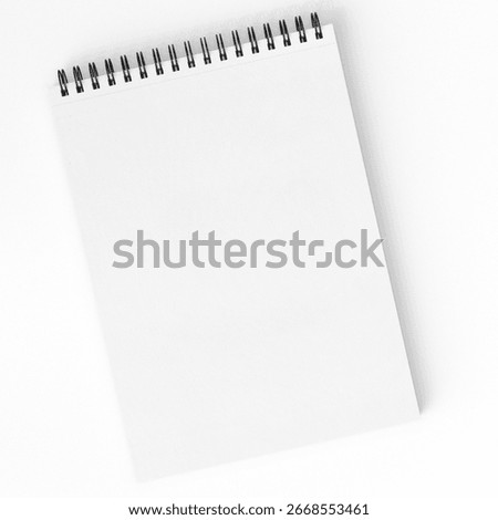 Empty sketchbook with spiral binding lying on white surface. Minimal stationery mockup for drawing, school, art, and creative projects. Top view.