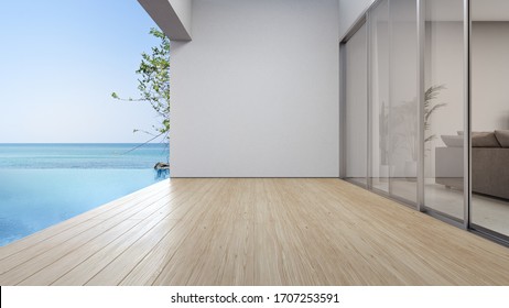 Empty Terrace Floor Near Living Room And White Wall In Modern Beach House Or Luxury Pool Villa. Wooden Deck 3d Rendering With Sea View.