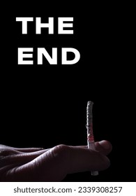 THE END poster. An extinguished cigarette in hand isolated on black background.