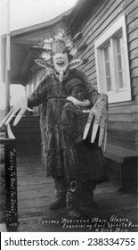 Eskimo medicine man in mask and sick boy, original title: 'Working to beat the devil, Eskimo medicine man exorcising evil spirits from a sick boy', circa 1900-1930.