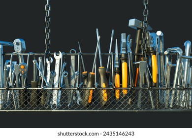 An extensive selection of hand tools neatly organized within a wire mesh basket, suspended against a stark black backdrop, epitomizing efficiency in a workspace setting. - Powered by Shutterstock