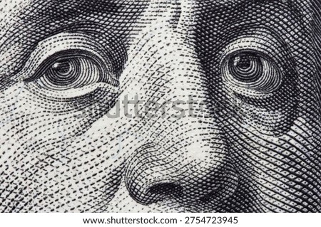  Extreme macro close-up of Benjamin Franklin's eyes on a one hundred US dollar bill. Business, finance and wealth concept. Concept of corruption, greed, bribery, or financial investigation.