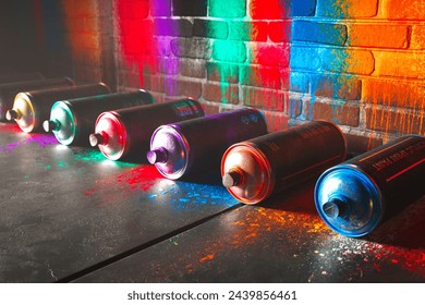 An eye-catching setup of aerosol paint cans scattered on a gritty surface, contrasted by a vividly graffiti-adorned brick wall, showcasing the essence of urban street art culture.