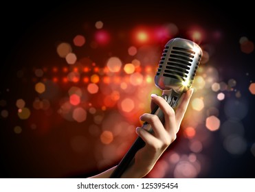 Female hand holding a single retro microphone against colourful background - Powered by Shutterstock