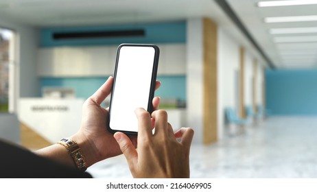 A Female Hands Using A Modern Smart Mobile Phone Over Blurred Hospital Or Clinic Reception Room In The Background. Phone Blank Screen Mockup. Closeup Image. 3d Rendering, 3d Illustration