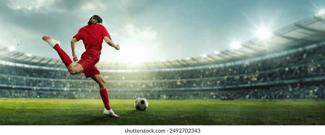 Female soccer player in red kicks ball on stadium field. Arena filled with enthusiasts, and field brightly lit with sunlight and spotlights. Concept of sport, championship, team game, tournament. Ad - Powered by Shutterstock