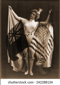 Female vaudeville performer in white body suit, wearing a cape of U.S. and British flags. The 'special relationship' between the two nations solidified in the post civil war era. 1899.