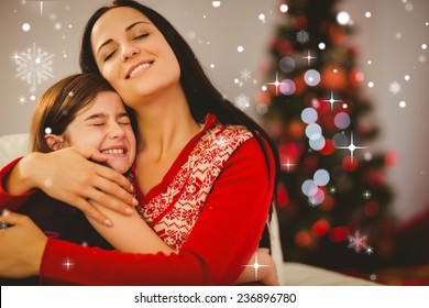 Festive mother and daughter hugging on couch against snow falling - Powered by Shutterstock