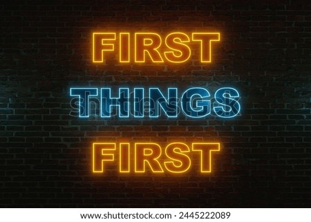 First things first. Brick wall at night with the text "first things first" in orange and blue neon letters. Important, in order, strategy, priorety.  3D illustration 