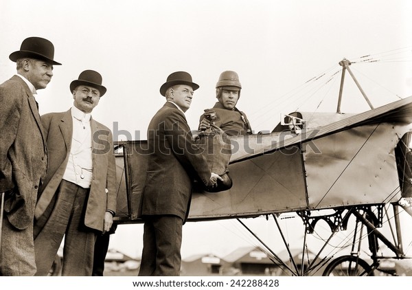 The first\
U.S. air mail pouch is handed to helmeted pilot Earle Ovington by\
Postmaster General Frank H. Hitchcock on Nassau Boulevard, Long\
Island, September 23,\
1911.