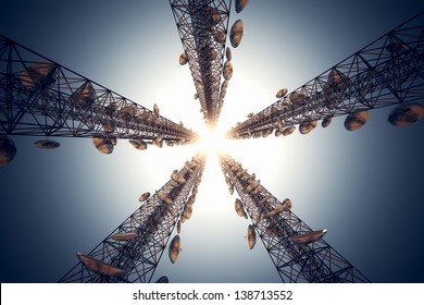 Five tall telecommunication towers with antennas on blue sky. View from the bottom.