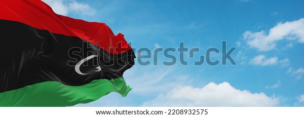 flag of Arab peoples Libyans at cloudy sky
background, panoramic view.flag representing ethnic group or
culture, regional authorities. copy space for wide banner. 3d
illustration