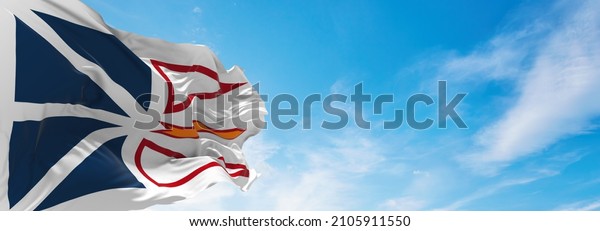 flag of\
Newfoundland and Labrador , Canada at cloudy sky background on\
sunset, panoramic view. Canadian travel and patriot concept. copy\
space for wide banner. 3d\
illustration