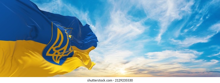 flag of Ukraine with coat of arms , Ukraine at cloudy sky background on sunset, panoramic view. Ukrainian travel and patriot concept. copy space for wide banner. 3d illustration