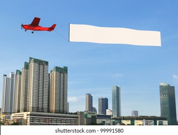 Flying banner pulled by airplane flying over a modern city building - Powered by Shutterstock