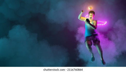 A Flying Excited And Impressed Man In Casual Clothes Holding Mobile Phone. Glowing Wings And Crown. Night Sky Neon Illumination. 3d Illustration