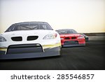 Front view of auto racing race cars racing on a track with motion blur. 