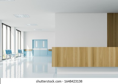 Front View Of Clean Modern Hospital Corridor With Big Windows, Rows Of Blue Chairs And Wooden Reception Desk. Concept Of Healthcare. 3d Rendering