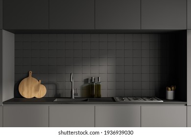 Front View Close Up Of Dark Grey Modern Kitchen Interior With Kitchenware. Concrete Floor. Black Facades And Ceramic Tiles On Wall. 3d Rendering.