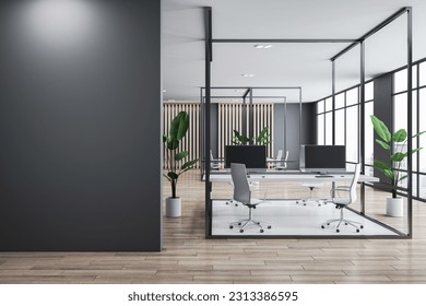 Front view on blank black wall with place for advertising poster or text in stylish sunlit coworking office with grey wall background and stylish workspace in metal frame. 3D rendering, mock up