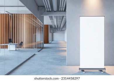 Front view on blank white rollup poster with space for logo or text on grey partition background on concrete floor in spacious office with wooden walls and glass doors. 3D rendering, mockup