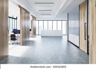 Front view of a white open office interior with panoramic windows, wooden walls, computer monitors on desks and a reception counter in the lobby. 3d rendering, mock up