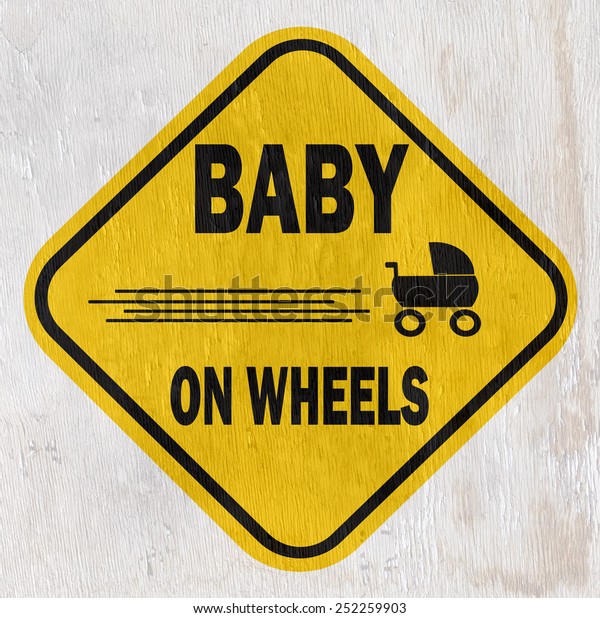 funny baby on\
wheels sign on wood grain\
texture