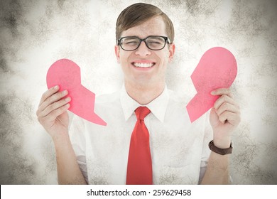 Geeky hipster holding a broken heart card against grey background
