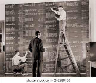 General Motors managers at a large control board, which resembles a spreadsheet, keep check on flow of materials needed for the wartime production. 1941.