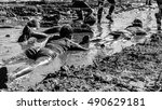 Girls crawling through mud doing an obstacle race, black and white