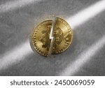 A golden Bitcoin coin split in half on concrete background, concept of Halving, an event that occurs in btc approximately every four years and divides miners