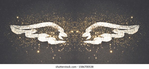 Golden glitter on abstract blue watercolor wings on black background