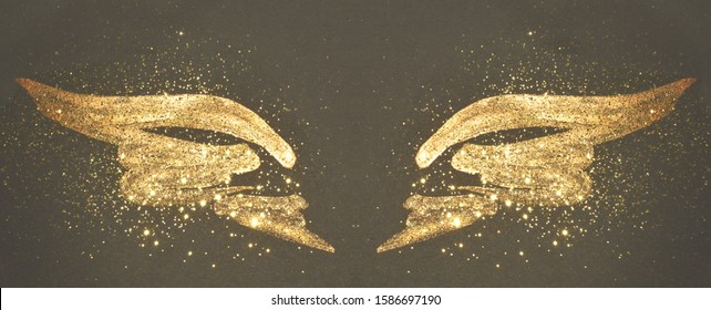 Golden glitter on abstract gold hand painted wings on black background