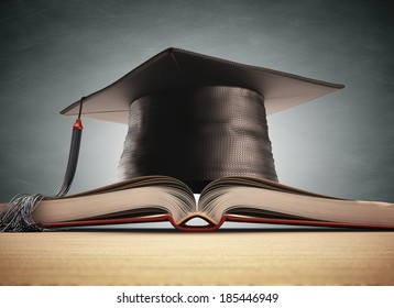 Graduation cap over the book with blackboard on background. Clipping path included.