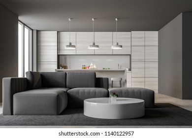 Gray Kitchen Interior With A Bar And Loft Windows. A Living Room With A Gray Sofa And A Round Coffee Table In The Foreground. 3d Rendering Mock Up