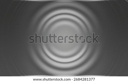 A grayscale image featuring concentric circles emanating from the center, creating a ripple effect.